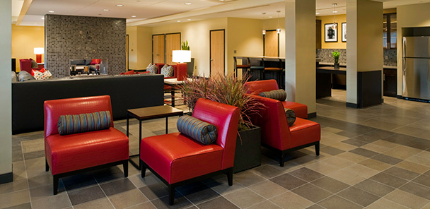 The Club Room at Harmony Oaks, with bright red upholstered chairs, fireplace and community kitchen.